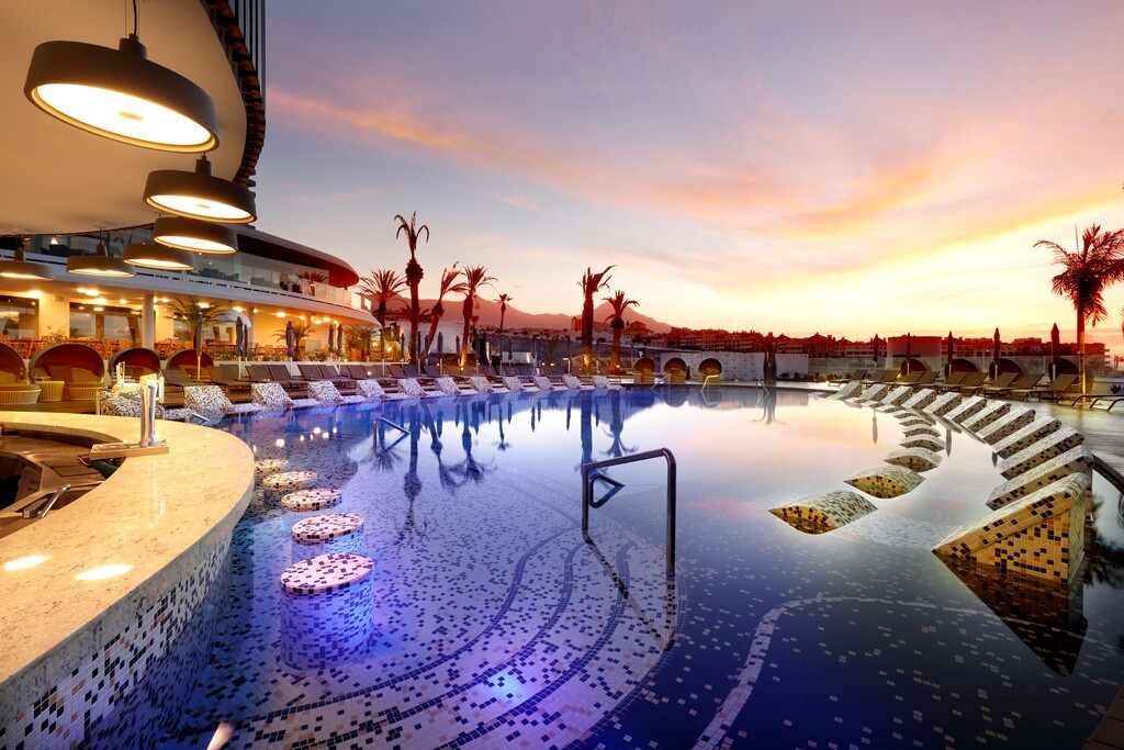 Schwimmbad bei Sonnenuntergang in einem Hotel auf Teneriffa, mit moderner Beleuchtung und Liegeplätzen.