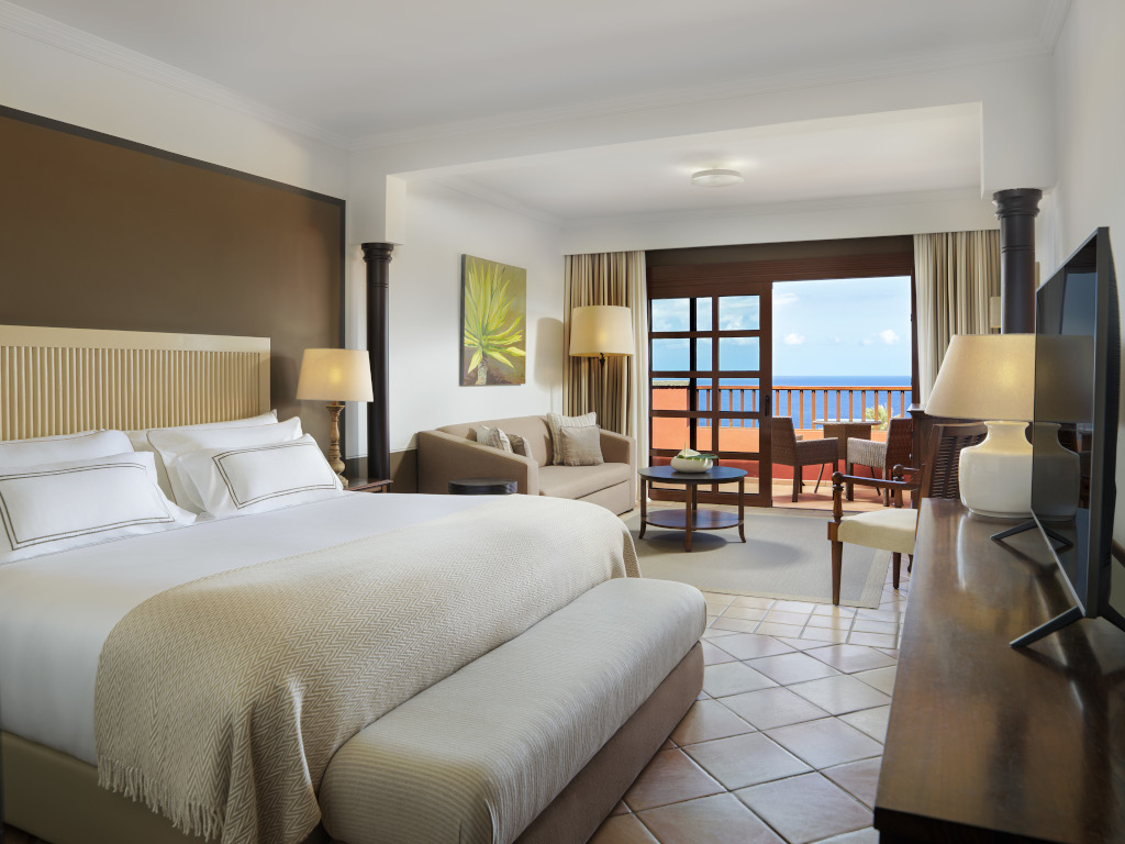Hotelzimmer auf Teneriffa mit Bett, Wohnzimmer und Balkon mit Blick aufs Meer.