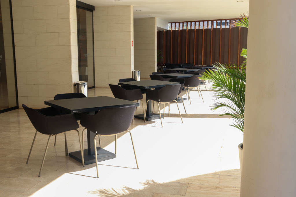 Terrasse mit schwarzen Tischen und Stühlen auf Teneriffa, mit natürlichem Licht und dekorativen Pflanzen.