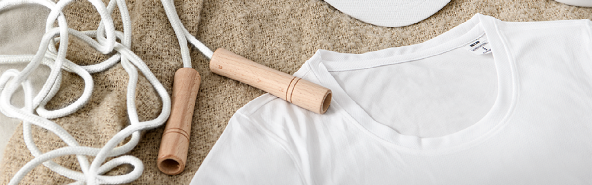 Weißes T-Shirt und Springseil im beigefarbenen Pullover.