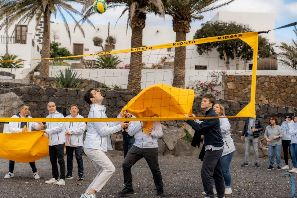Menschen, die Volleyball mit einem gelben Tuch in einem Innenhof auf Teneriffa spielen.
