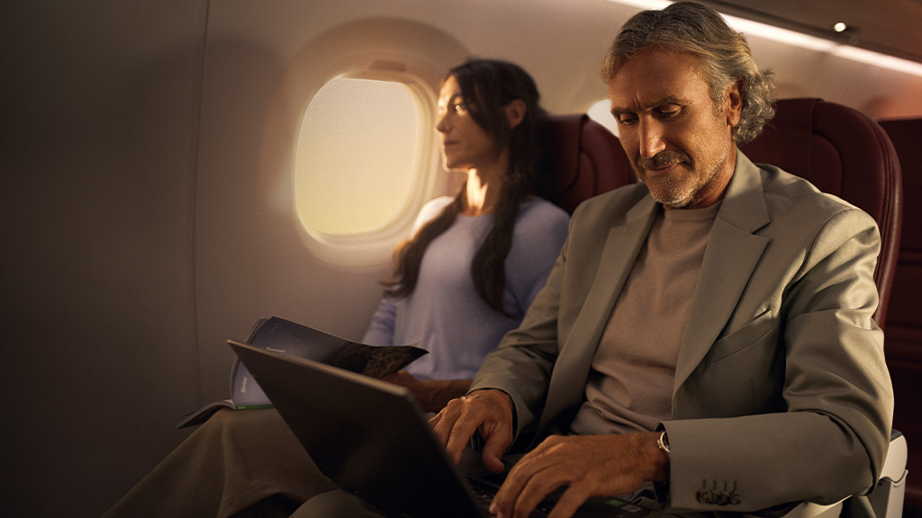 Mann mit Laptop, Frau liest im Flugzeug mit natürlichem Licht.