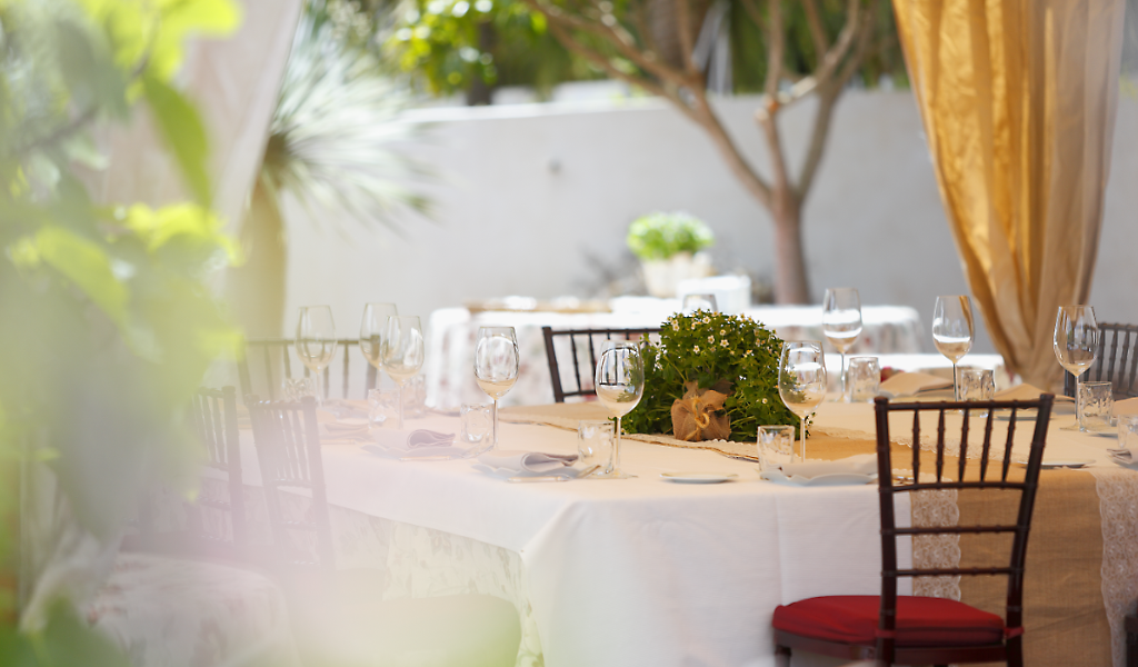 Tisch mit Gläsern und Blumen-Mittelstück in einem Open-Air-Restaurant auf Teneriffa.