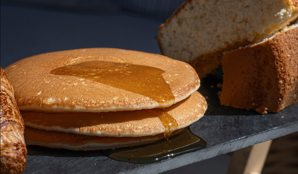 Pfannkuchen mit Sirup und einem Biskuitkuchen auf einem Blech.