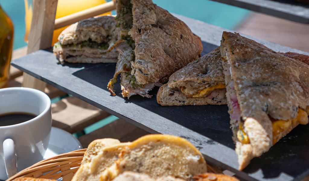 Schinken-Käse-Sandwiches auf einem Brett, mit einer Tasse Kaffee, auf einer Terrasse auf Teneriffa.