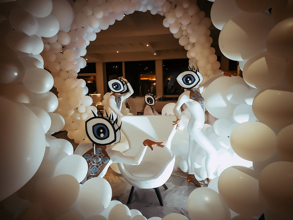 Menschen in weißen Kostümen mit Augenmasken umgeben von Luftballons in Tenerife.