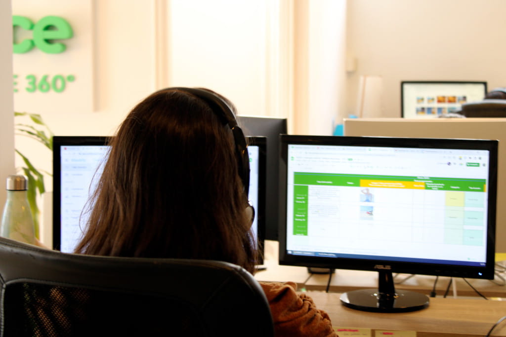 Person mit Kopfhörern arbeitet an zwei Bildschirmen im Büro in Tenerife.