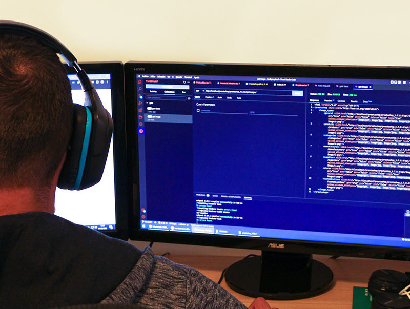 Entwickler trägt Kopfhörer und arbeitet an Code auf zwei Bildschirmen in Tenerife.