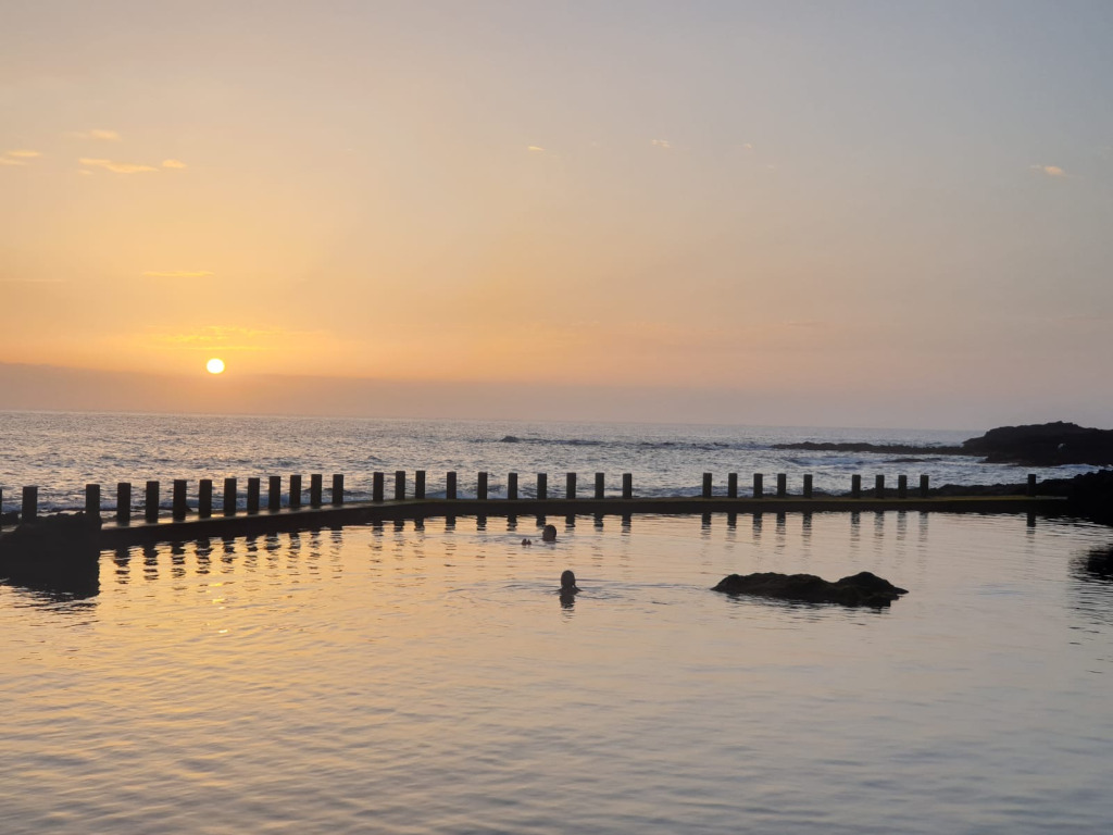 Sonnenuntergang über natürlichem Pool in Teneriffa mit schwimmender Person.