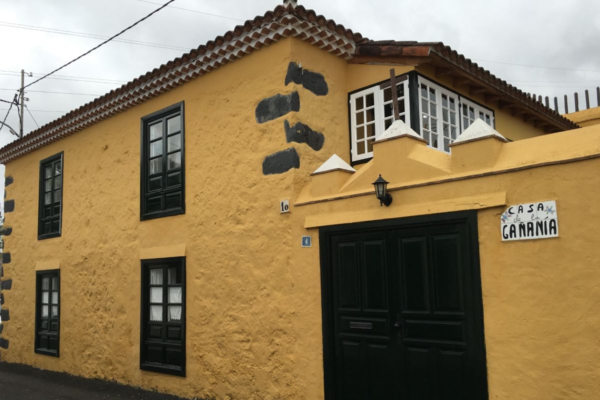Gelbes Haus mit dunklen Fenstern und Schild Casa de la Ganania in Teneriffa.