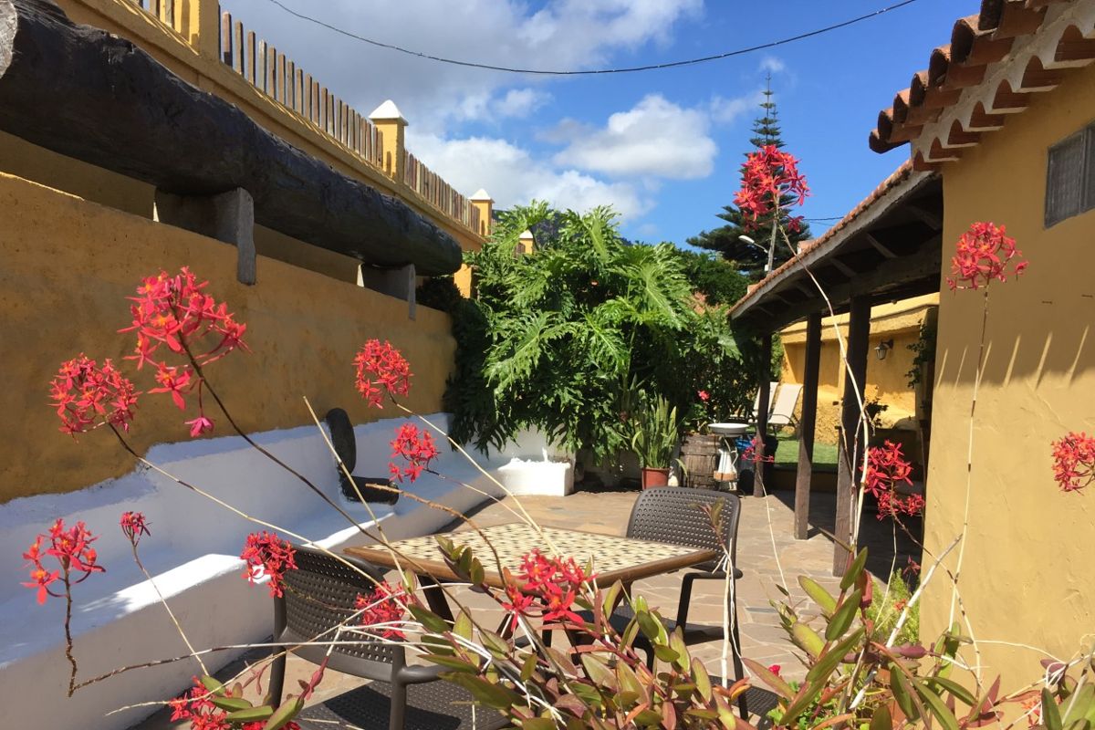 Hof mit roten Blumen und gelbem Haus in Teneriffa.