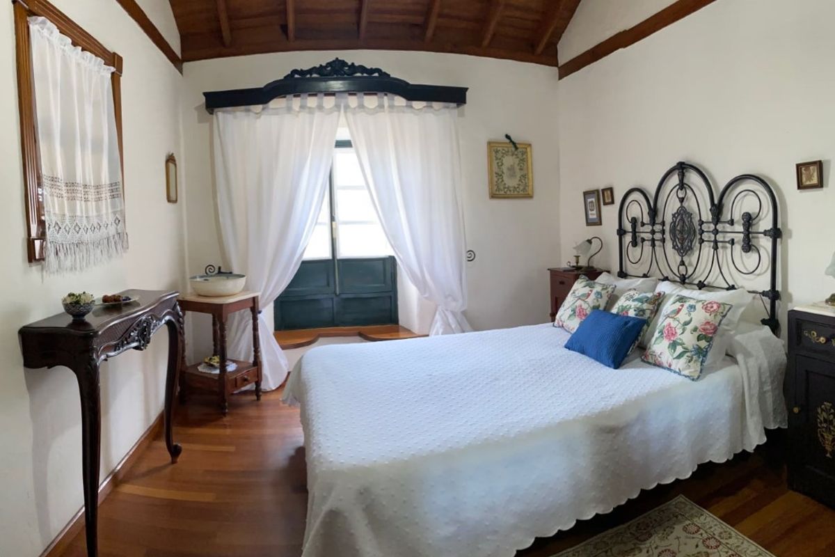 Schlafzimmer mit Doppelbett, Holzmöbeln und Vorhängen in einem Haus in La Orotava, Teneriffa.