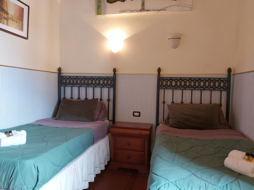 Zwei Einzelbetten mit Holz-Nachttisch in einem Zimmer in Teneriffa.