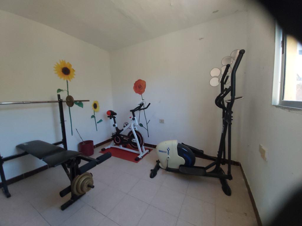 Fitnessraum in Teneriffa mit Hantelbank, Heimtrainer und Ellipsentrainer.