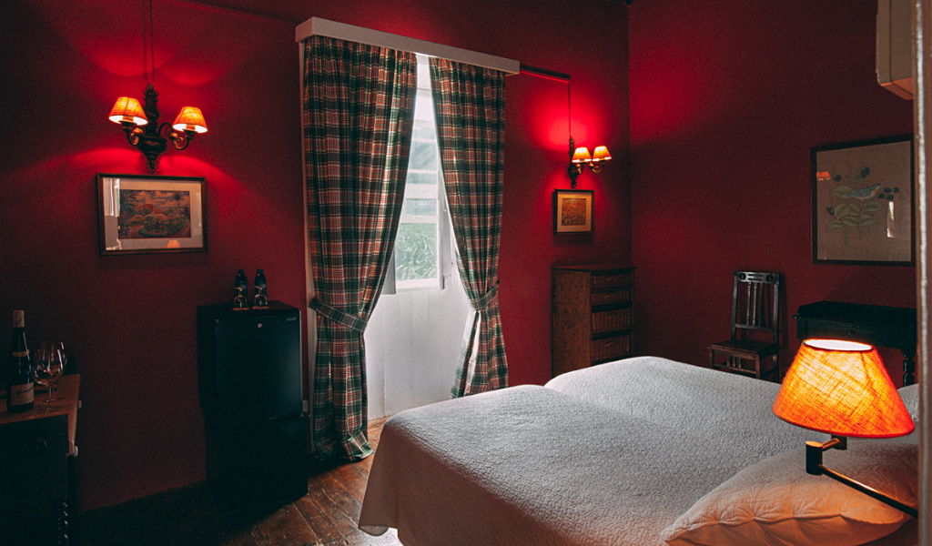 Zweibettzimmer mit roten Wänden, Fenster und Lampe in einem Hotel in Teneriffa.
