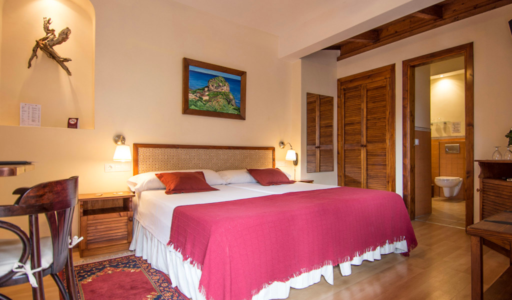 Hotelzimmer in La Laguna mit Doppelbett, roter Decke, Holzmöbel und Wandkunst.