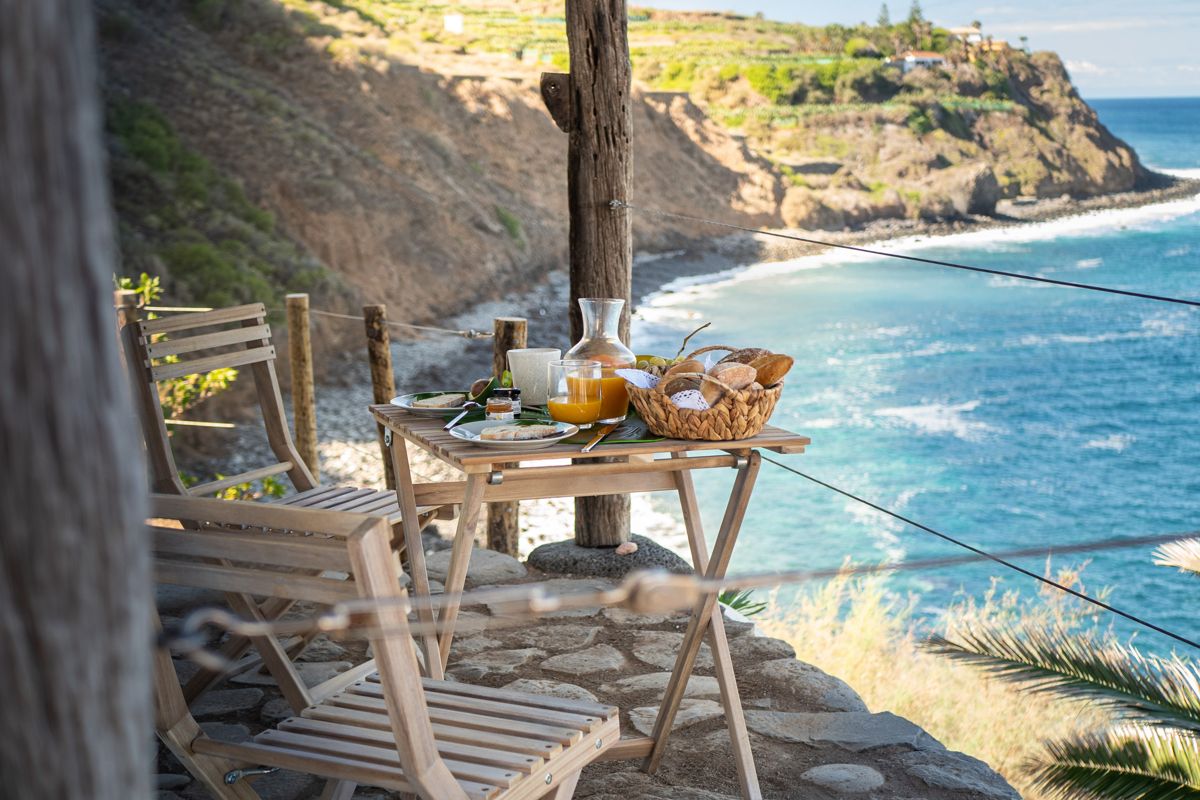 Frühstückstisch mit Meerblick auf Küste von Tenerife, Brot, Saft und Gebäck.