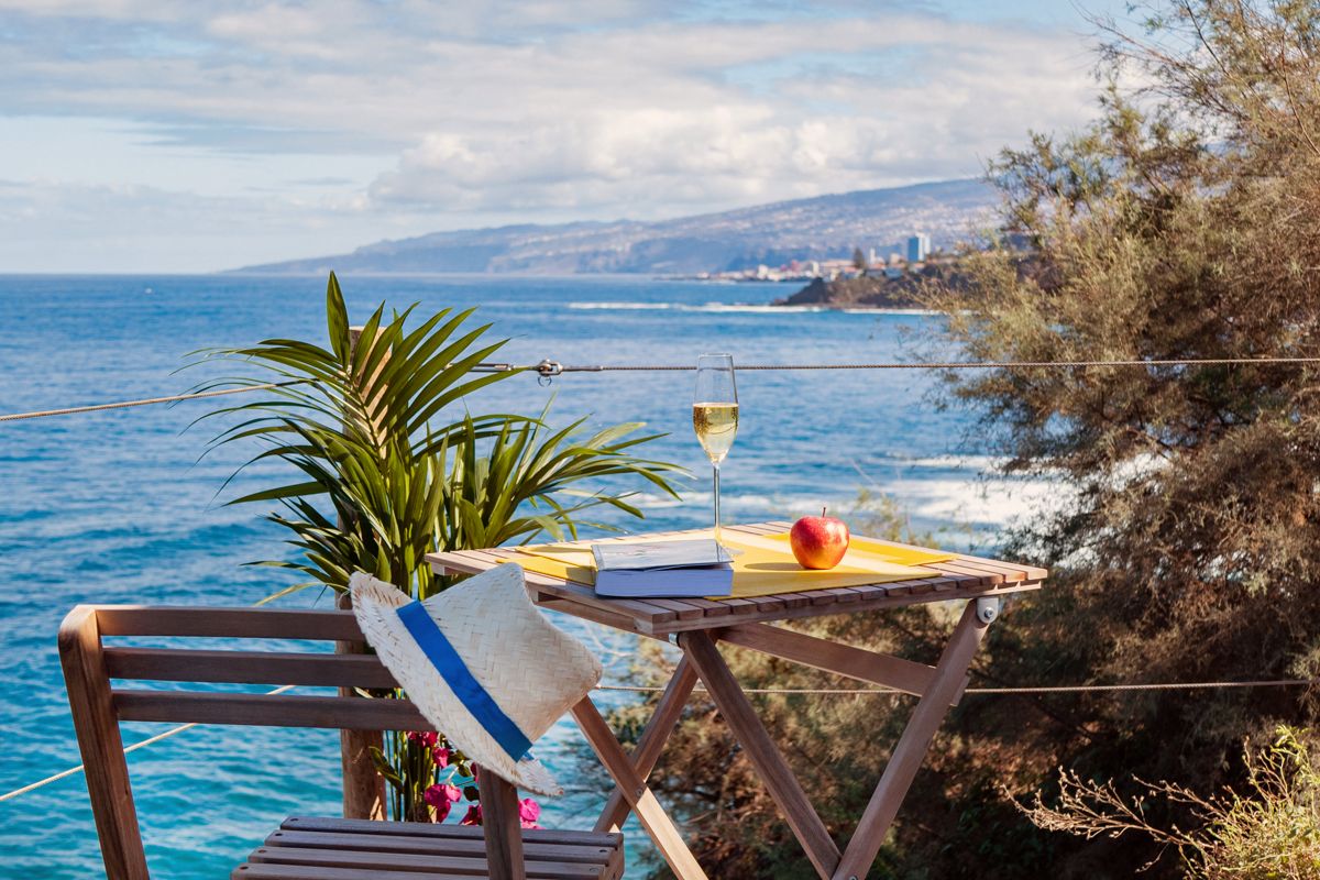 Tisch mit Apfel, Buch und Weinglas am Meerblick in Puerto de la Cruz, Teneriffa.