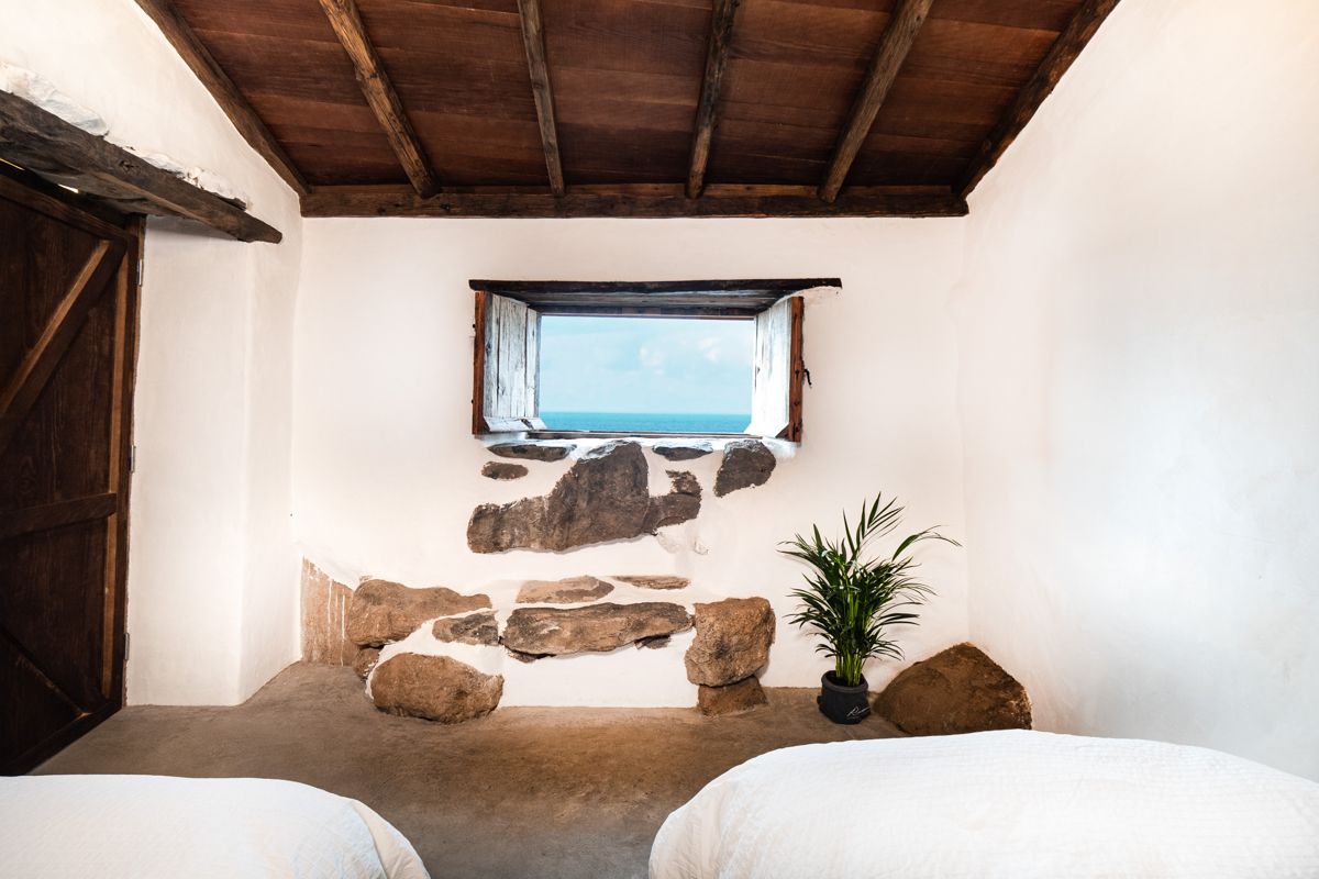 Raum mit Blick auf den Ozean durch Fenster, Steinwand und Pflanze in Icod de los Vinos.