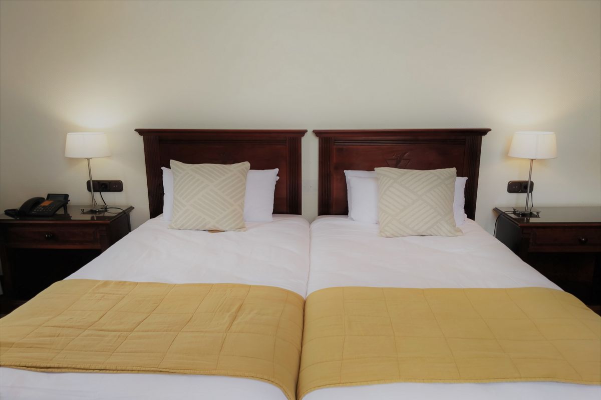 Zwei Einzelbetten mit gelben Überdecken und Nachttischen in einem Hotelzimmer in Teneriffa.