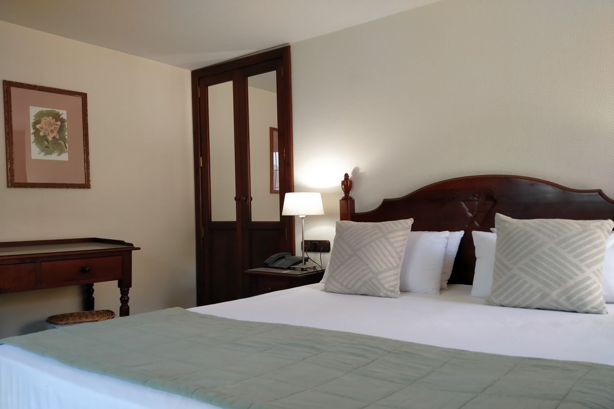 Doppelbett mit Holzrahmen, Nachttischlampe und Tür in einem Hotelzimmer in Tenerife.
