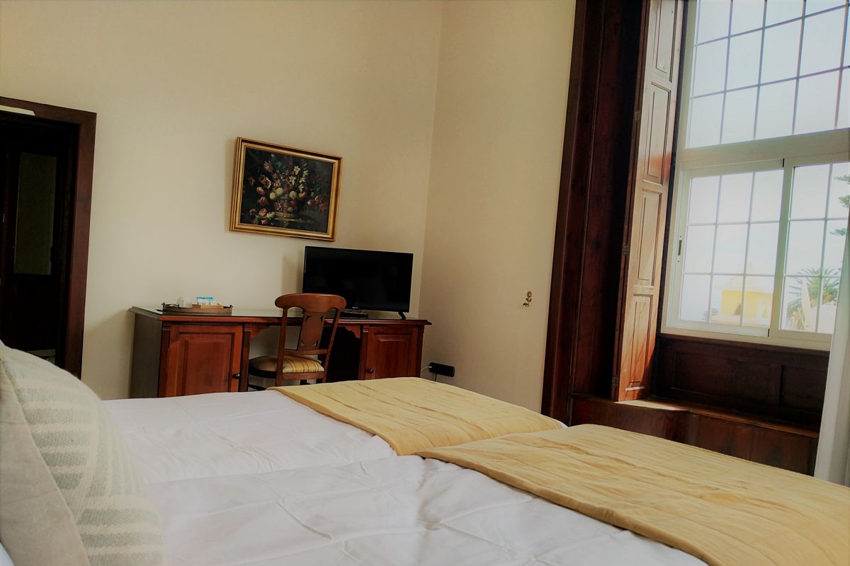 Bett, Schreibtisch, Stuhl und Fenster mit Blick auf Puerto de la Cruz in einem Raum.