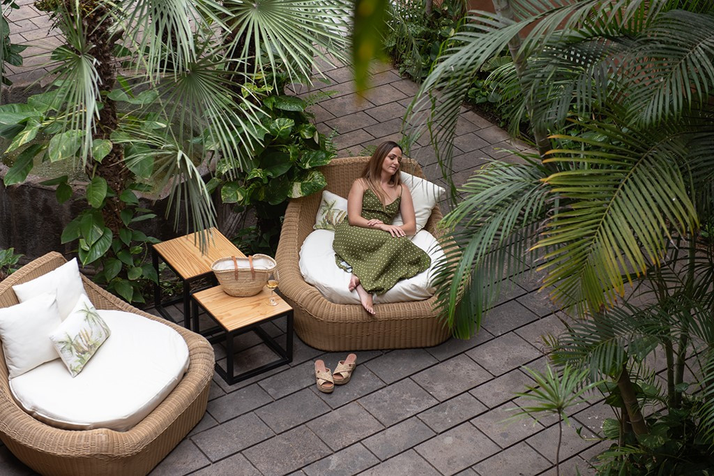 Frau sitzt in einem Gartenstuhl zwischen Palmen im Hotel in Puerto de la Cruz.