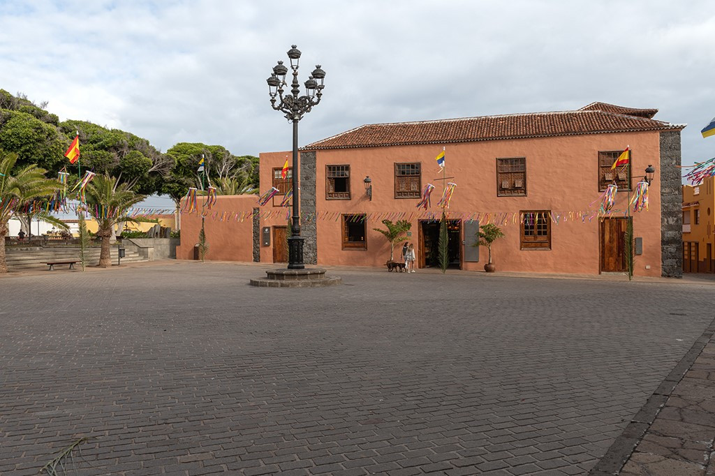 Historisches Gebäude in La Orotava mit Flaggen und Lampenpfosten auf gepflastertem Platz.