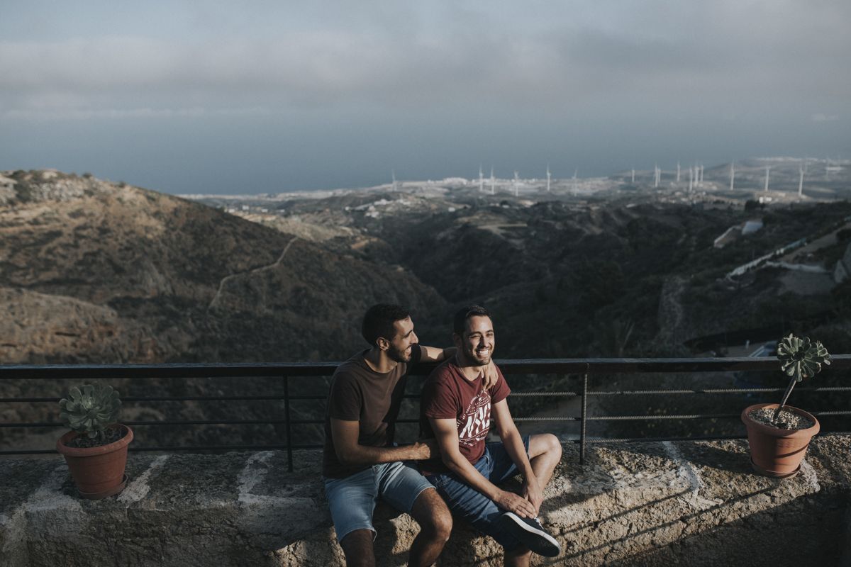 Zwei Personen sitzen auf einer Mauer mit Blick auf die Landschaft Teneriffas.