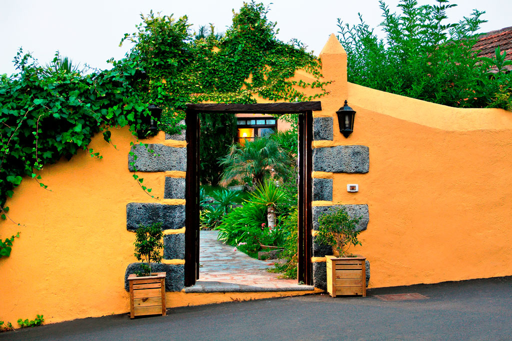 Offenes Tor in gelber Mauer, führt zu einem Garten in Puerto de la Cruz.