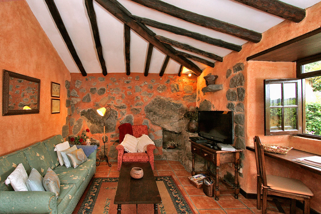 Gemütliches Wohnzimmer mit Steinwänden, Sofa, Sessel und TV in La Orotava, Teneriffa.