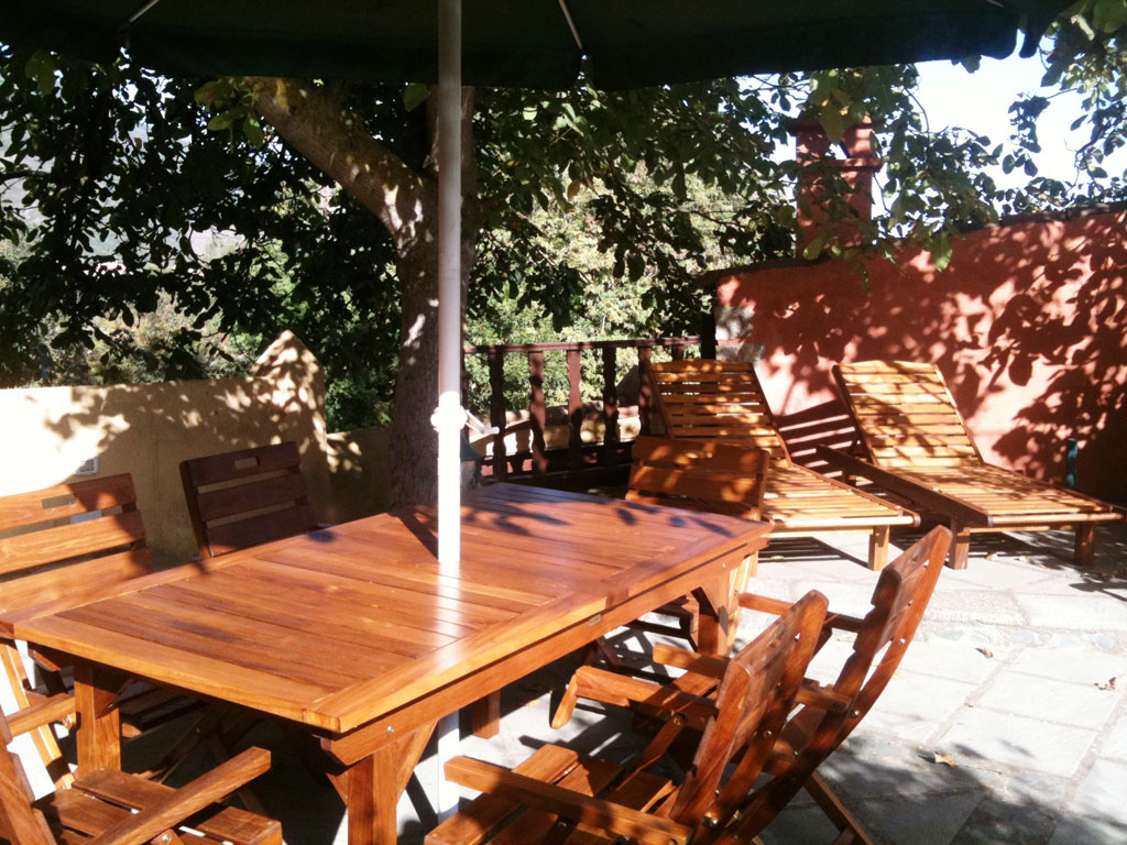 Holzmöbel auf sonniger Terrasse mit Bäumen im Hintergrund in La Orotava, Teneriffa.