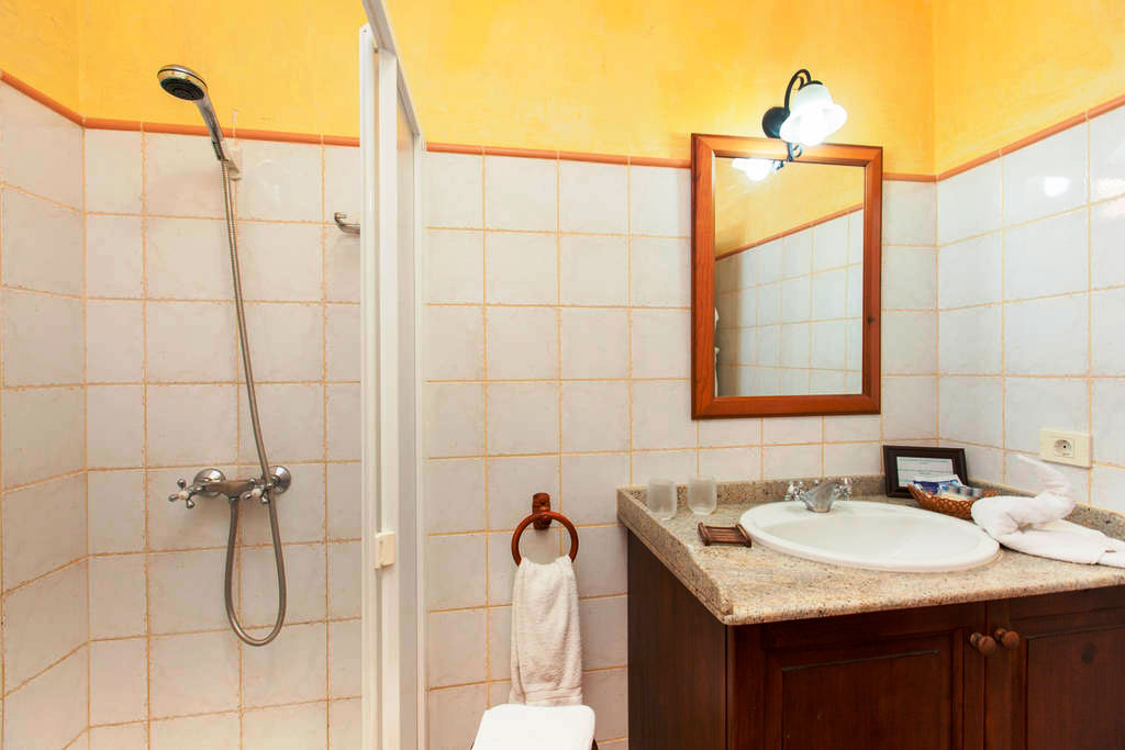 Badezimmer mit Dusche, Spiegel und Waschbecken in einem Hotel in Teneriffa.