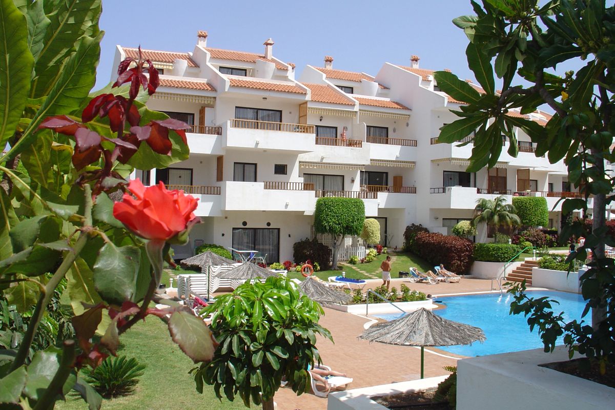 Wohnanlage mit Pool und Garten in Teneriffa, umgeben von Pflanzen und Blumen.