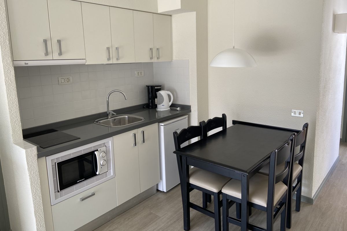 Kleine Küchenecke in Ferienwohnung in Teneriffa mit Tisch und Stühlen.