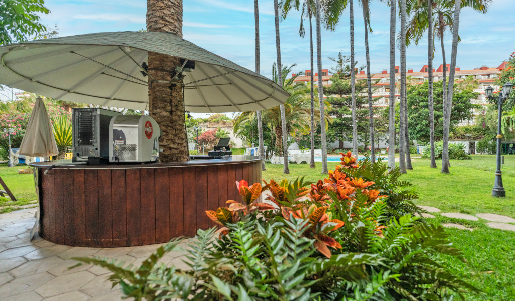 Außenbar mit Sonnenschirm und Pflanzen in einer Gartenanlage in Tenerife.