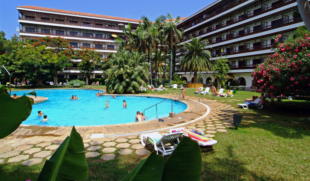 Hotelpool und Garten in Puerto de la Cruz, Teneriffa mit Gästen und Liegestühlen.