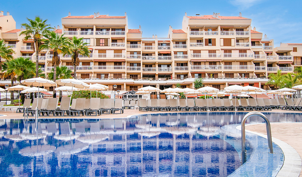 Hotel mit Pool und Liegestühlen in Los Cristianos, Teneriffa.