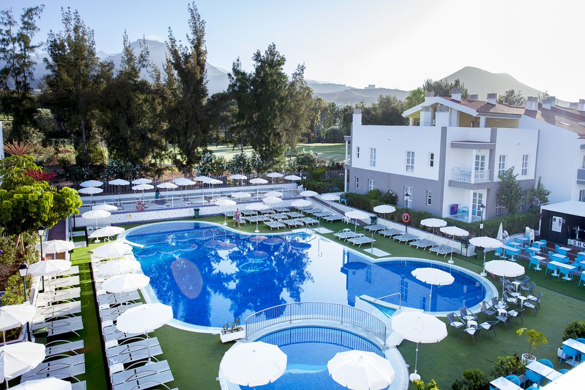 Poolbereich mit Liegen und Sonnenschirmen in Hotelanlage in Adeje, Teneriffa.