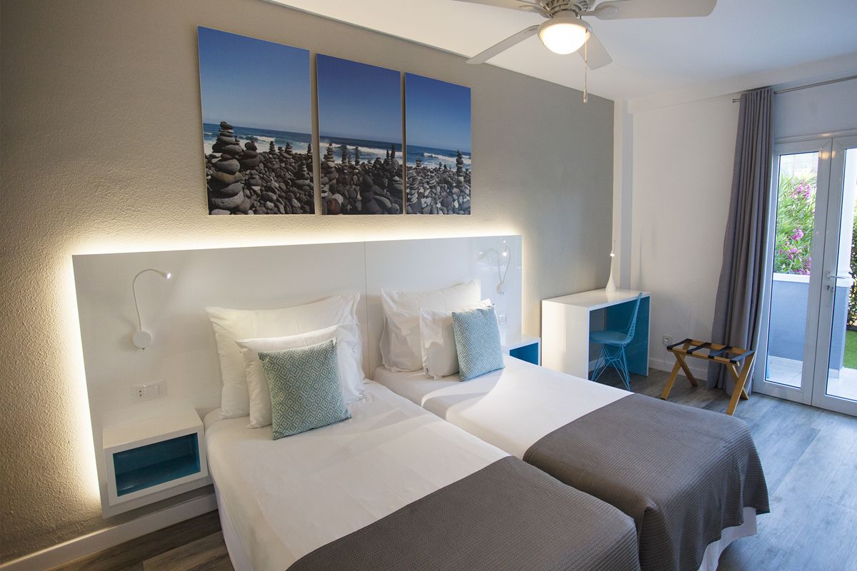 Zwei Einzelbetten mit blauer Bettwäsche im Hotelzimmer, Puerto de la Cruz.