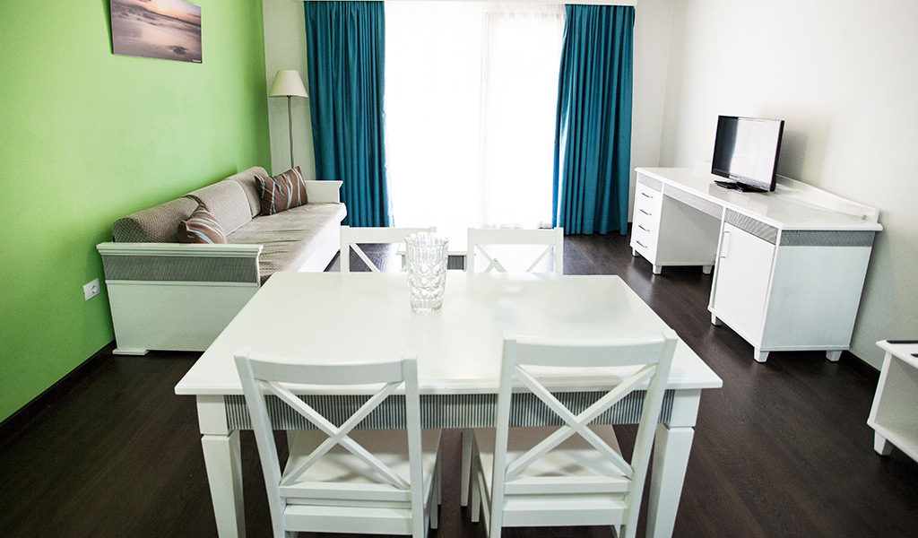 Wohnzimmer in Puerto de la Cruz mit Tisch, Sofa, TV und blauen Vorhängen.