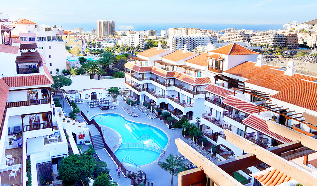 Apartmentanlage in Los Cristianos, Tenerife, mit Pool und umliegender Stadtblick.