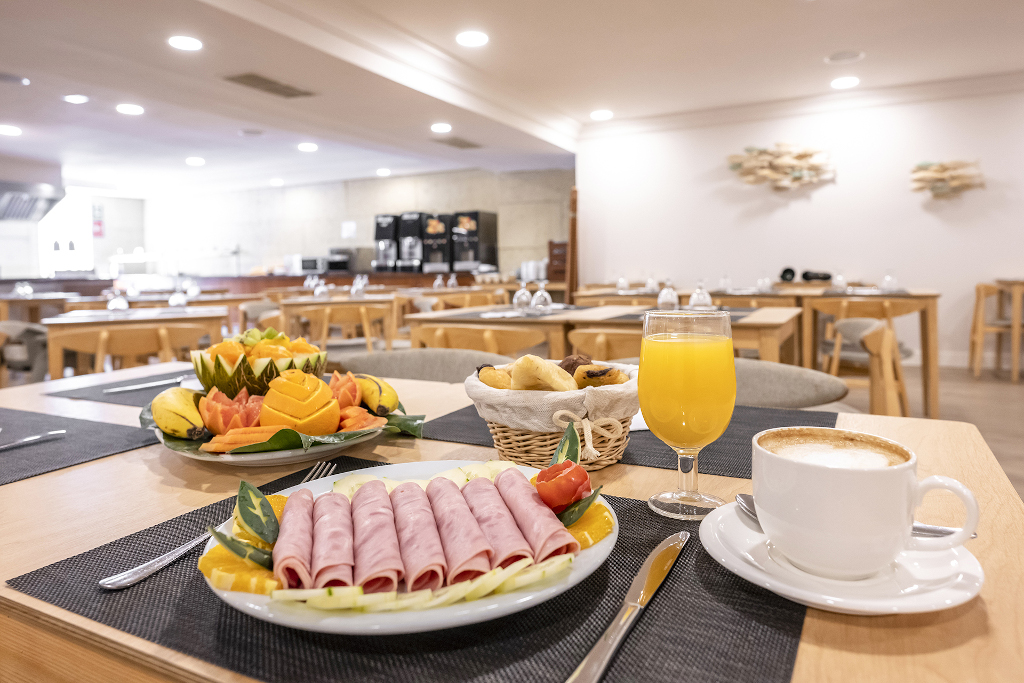 Frühstückstisch mit Schinkenrollen, Saft, Kaffee und Obst in einem Cafe in Tenerife.