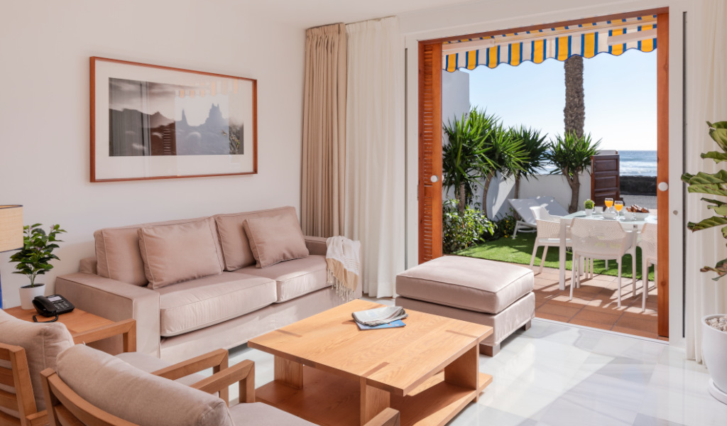 Wohnzimmer mit offener Tür zum Garten mit Meerblick in Teneriffa.