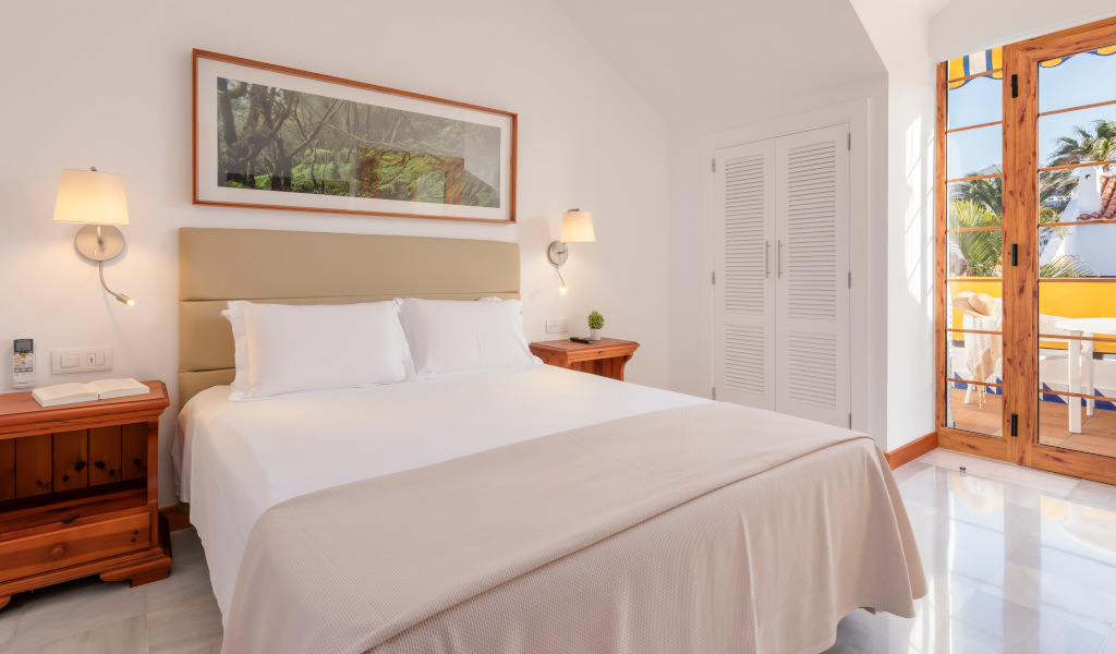 Schlafzimmer mit Doppelbett, Nachttischen, Kunstbild und Terrasse in Tenerife.
