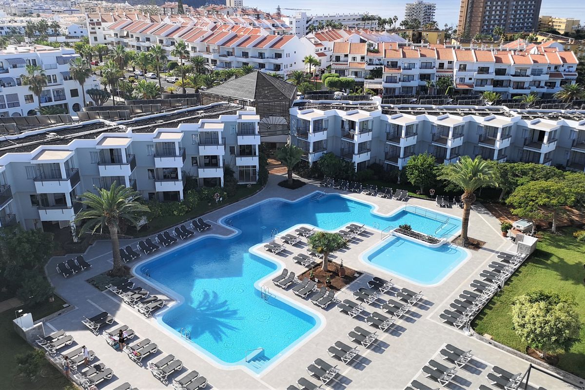Wohnanlage in Playa de las Américas mit Pool und Sonnenliegen.