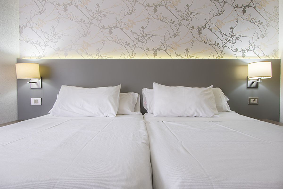 Zwei Einzelbetten mit Wandlampen im Hotelzimmer in Tenerife.