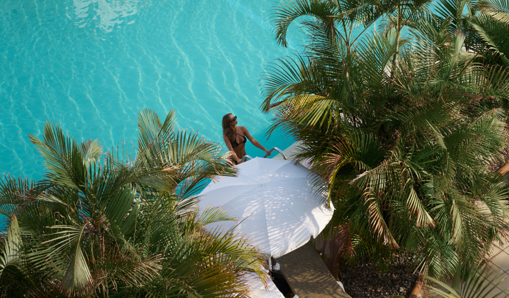 Frau im Bikini am Rand eines Pools unter Palmen in einem Resort in Tenerife.