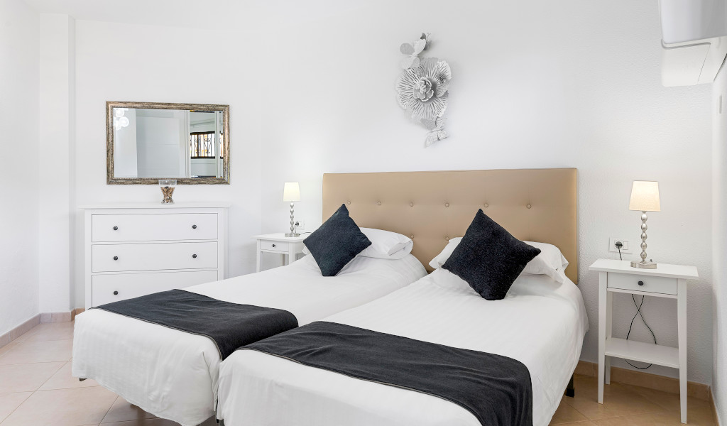 Zwei Betten mit weißen Laken und dunklen Kissen in einem Zimmer in Puerto de la Cruz, Teneriffa.