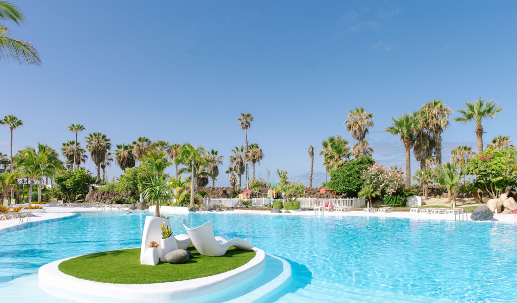 Pool mit Palmen und Liegestühlen in Costa Adeje, Teneriffa.